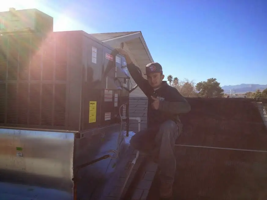 HVAC technician performing AC Tune-Up on a rooftop unit in Medina
